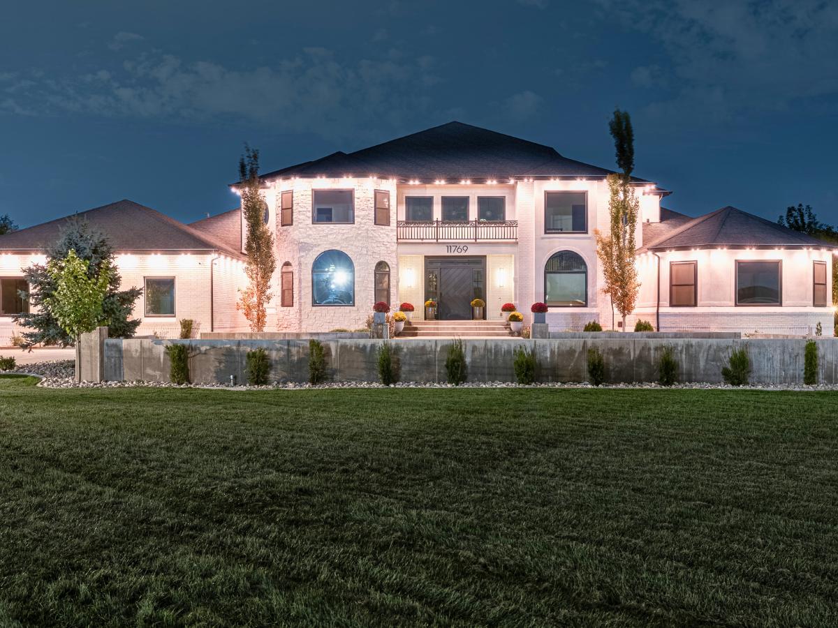 Warm white permanent outdoor lights on a large home at night