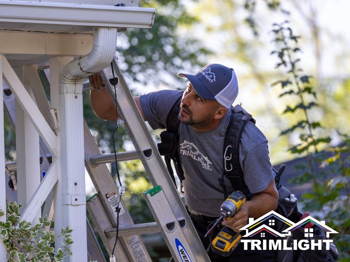 Trimlight installer mounting permanent LED track under a roofline