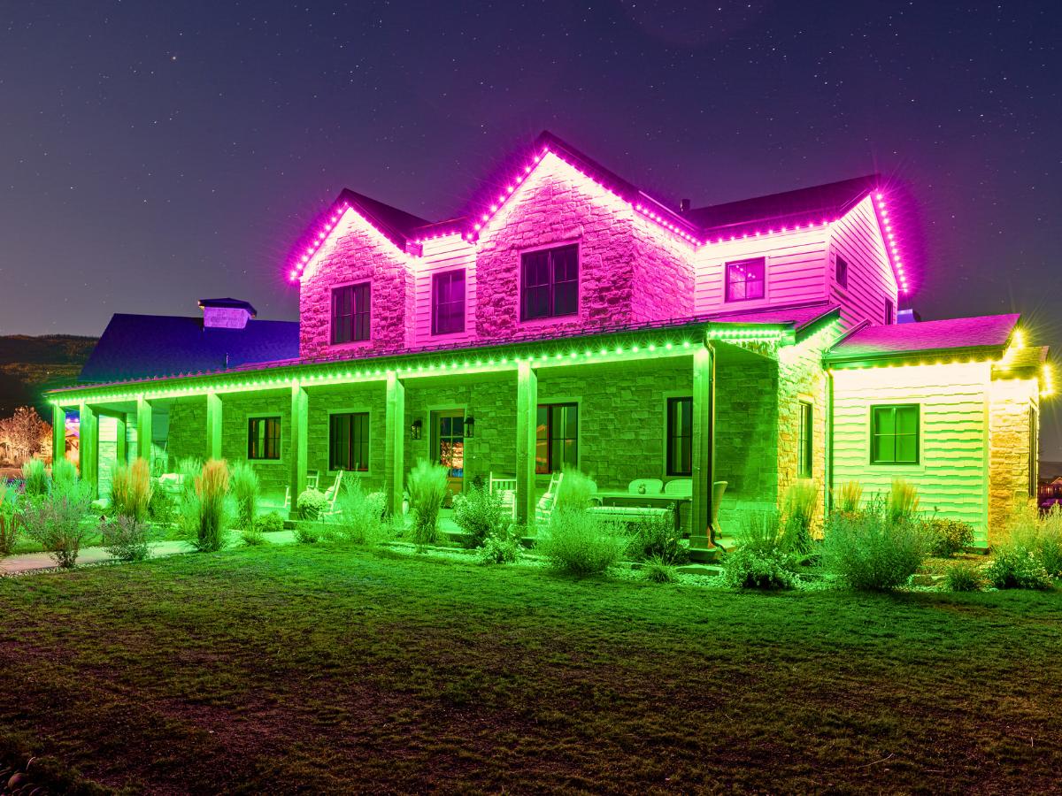 Pink and green permanent outdoor lights on a large home